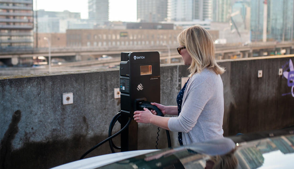 A woman charging her car at a commercial EV charger